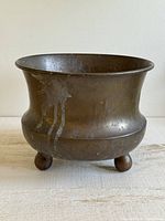 Frontal view showing flared rim, patina, and knob feet