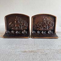 Front view of both metal bookends with sailing ship relief