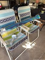 two striped folding chairs, folded umbrella, sand anchor