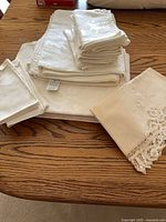 Stacked tablecloths, napkins, lace runner showing color and pattern