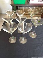 Seven stemmed martini glasses on table, four plain and two with olive design visible
