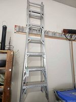 Folded aluminum extension ladder hanging on wall