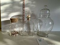 Three clear lidded glass containers of varying shapes and sizes placed side by side for size comparison