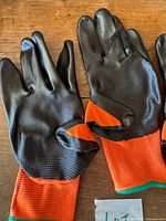 Two gloves showing black rubber palms and orange backs