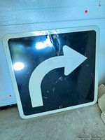 Front view of square traffic sign with right-turn arrow, shows wear and crease