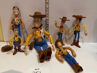 Group shot of six Woody figures and extra hat