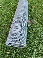 Full roll of grey plastic mesh fencing on grass