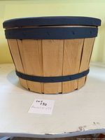 Front view of wooden basket with painted lid and straps