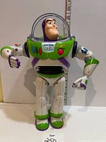 Front view of Buzz Lightyear figure standing, ruler for scale