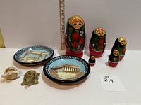 Full lot showing plates, matryoshka set, turtle figurines with ruler for scale