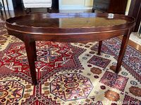 Full perspective view of mahogany oval coffee table on patterned rug