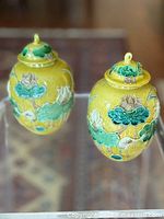 two matching yellow ginger jars with lids displayed