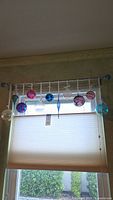 All eleven glass ornaments hanging on rod showing colour variety and cords