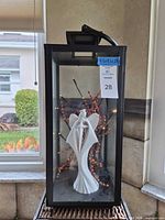 Full view of black metal and glass display cabinet showing front, top handle, contents for scale