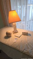 Lamp illuminated with shade, capiz shell sphere, square tile, and cube box on table