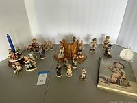 Group shot showing all 23 figurines, candleholder with blue taper, reference book, plaque on stand