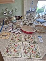 Countertop view of entire lot showing plates, bowls, mugs, bakeware, placemats, utensils