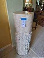 Full view of stone pedestal showing polished upper half and textured lower half