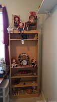 Overall view of shelving unit with dolls, wreath clock and assorted decor