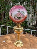 Full view of brass base and painted glass globe lamp on table
