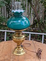 Full view of brass electrified oil lamp with green glass shade, chimney, and power cord
