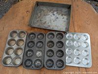 Top view of five metal baking pans including square pan and four 8-cup tart tins