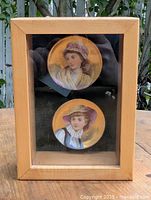 Front view of wood display case showing two ceramic plaques
