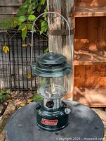 Full view of green Coleman camping lantern on table