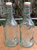 Front view of both embossed glass milk bottles with swing stoppers