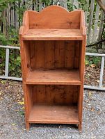 Front view of pine bookshelf showing three shelves and scalloped top