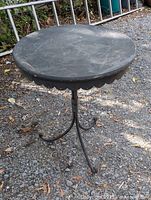 Full view of round metal garden table on gravel surface