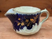 Side view showing cobalt blue glaze, gold floral décor, white lower portion, handle and spout
