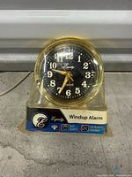 Front view of Equity brass-tone wind-up alarm clock in original packaging