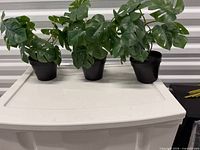 Three artificial plants on white surface