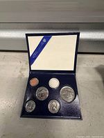 Open case showing six coins and interior ribbon