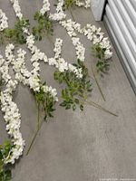 Bundles of white artificial flower garlands laid on floor showing length and leaf detail