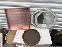 wire basket partially visible left, two octagonal mirrors leaning against wall