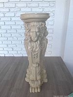 Front view of beige plaster pedestal with lion head and paw feet