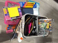 Overview of lot showing notebooks, zipper pencil case, glue, glue sticks, eraser, sticky notes, coloured pencils, paint brushes