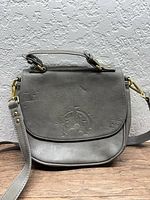 Front view of gray Disney purse showing embossed castle graphic and overall style