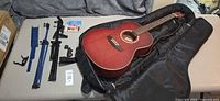 Guitar in open case with music stand parts and string pack on table