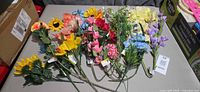 Full lot of assorted artificial flower stems laid out on table