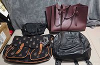 All four bags laid out: burgundy tote, black waist pack, pineapple messenger, black backpack