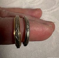 Both rings on finger showing color difference and engraving detail