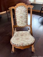 Full front view of wooden folding rocking chair showing floral upholstered back and seat