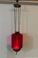 Ribbed red glass lantern hanging by four chains with brass canopy and base