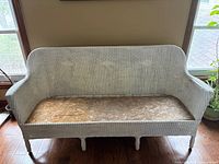 Front view of white wicker settee showing overall design and wooden seat board