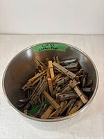 Stainless steel bucket containing wooden and plastic clothes pegs