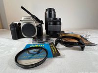 Canon EOS Elan body, two Canon lenses, filters and accessories arranged on table