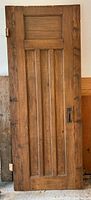 Full view of wooden panel door with handle and hinges